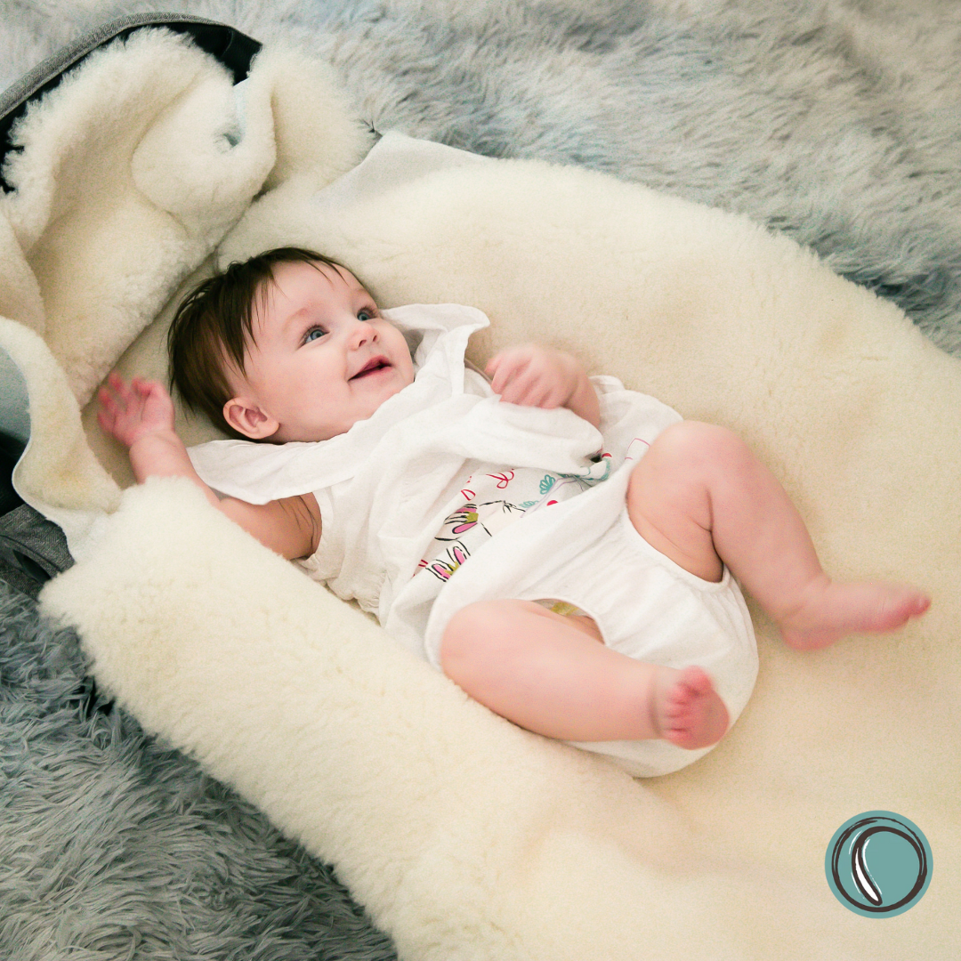 Baby lying on a soft natural merino sheepskin with a soft grey rug in the background